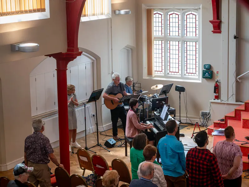 The music group leading sung worship at a Sunday service, with the congregation standing to sing